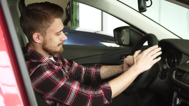 Junger Mann begutachtet Innenraum eines Neuwagens im Autohaus — Stockvideo