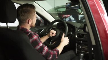 Neşeli yakışıklı erkek müşteri yeni bir araba galerisinde oturan yukarı başparmak gösterilen