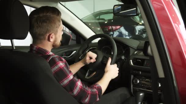 Χαρούμενη όμορφος αρσενικό πελάτη δείχνει μπράβο κάθεστε σε ένα καινούργιο αυτοκίνητο στην αντιπροσωπεία — Αρχείο Βίντεο