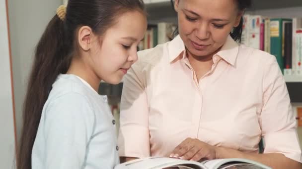 Мать и дочь выбирают книги в библиотеке или книжном магазине — стоковое видео