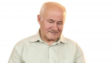 Yaşlı adam kameraya gülümseyen bir çalar saat bakarak