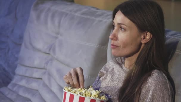 Nahaufnahme einer reifen Frau, die im Kino lächelnd Popcorn isst — Stockvideo