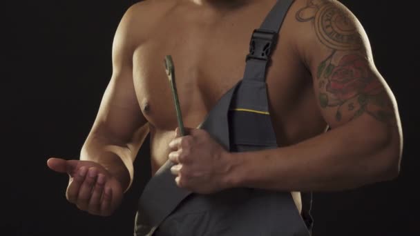 Roztrhl svalů mechanik v pracovní oděvy pohledu agresivní drží klíč — Stock video