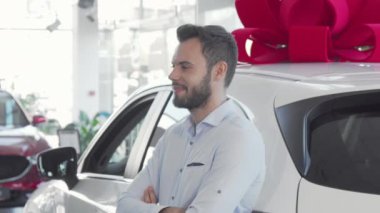 Çekici genç adam galeride yeni arabasının anahtarlarını tutuyor.