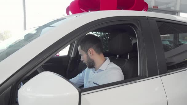Красивый веселый мужчина показывает ключи от машины на своей новой машине — стоковое видео