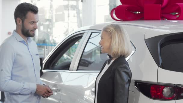 Femme souriant à la caméra tandis que son mari examine l'intérieur d'une nouvelle voiture — Video