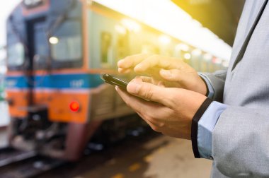 Tren platformu bekleyen işadamı ile smartphone,