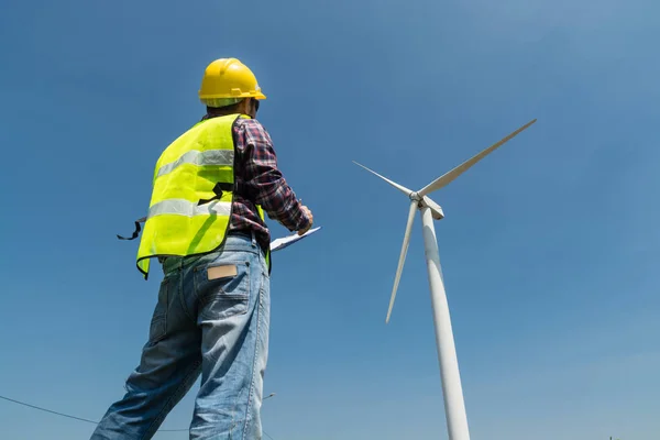 Electric Engineer writing report on Clipboard with Wind turbine