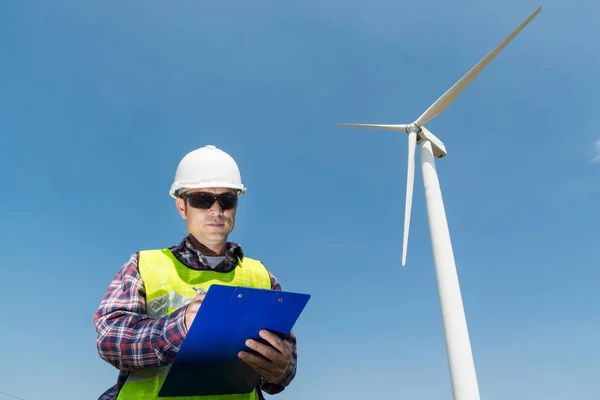 Electric Engineer writing report on Clipboard with Wind turbine — Stock Photo, Image