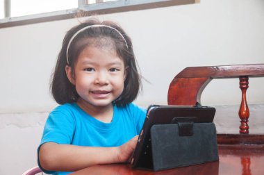 Asyalı Kız çevrimiçi kurs öğreniyor veya evde dijital kablosuz aygıt veya tablet üzerinden oyun oynuyor Teknoloji e-öğrenme kavramı olarak.