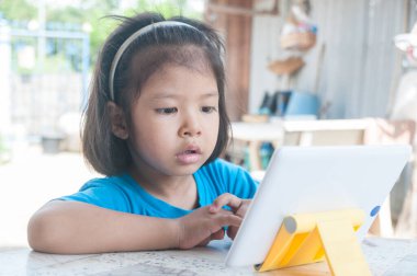 Asyalı Kız çevrimiçi kurs öğreniyor veya evde dijital kablosuz aygıt veya tablet üzerinden oyun oynuyor Teknoloji e-öğrenme kavramı olarak.