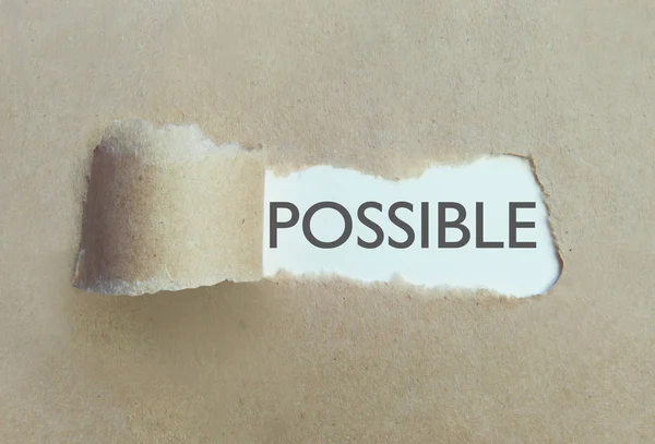 Torn brown paper uncovering the word possible — Stock Photo, Image