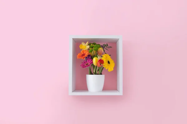 ピンクの壁紙に対するキューブ棚ディスプレイユニット内の春の花 — ストック写真