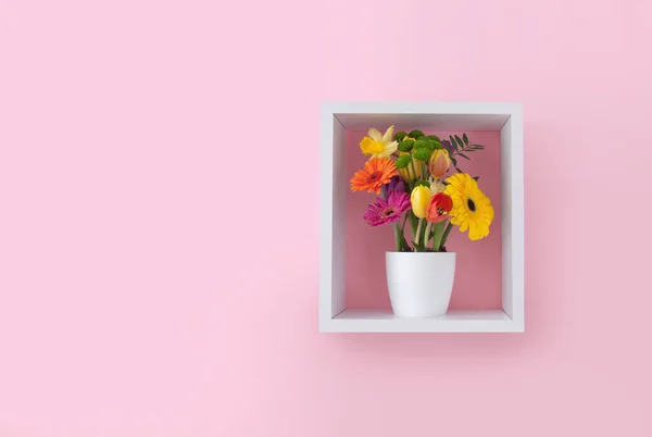 ピンクの壁紙に対するキューブ棚ディスプレイユニット内の春の花 — ストック写真