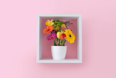 Pembe duvar kâğıdına karşı küp raf görüntüleme ünitesinde bahar çiçekleri 