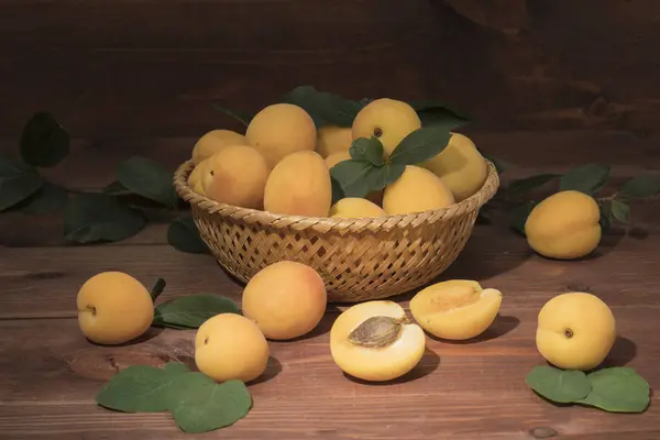 Fresh apricots on a wooden table with a basket — Stock Photo, Image