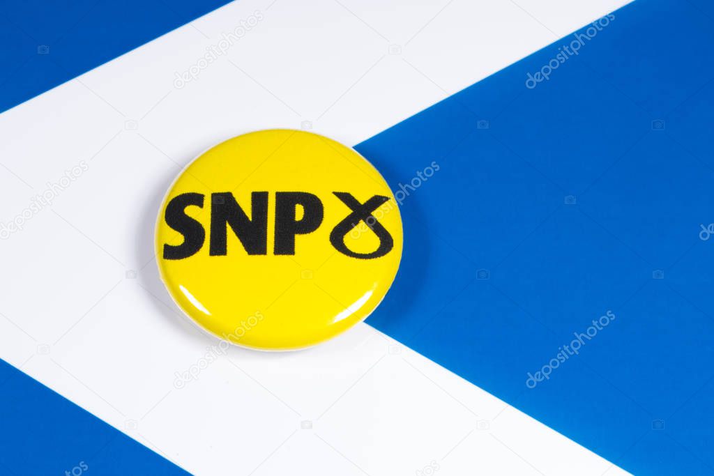 London, UK - December 3rd 2019: Scottish National Party pin badge, pictured over the Scotland flag.