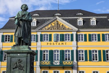 Ünlü besteci Ludwig van Beethoven 'ın heykeli. Arka planda, Almanya' nın Bonn kentindeki Munsterplatz 'da bulunan güzel eski postane binası.. 