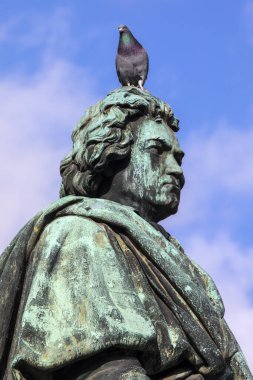 A Pigeon sits on the statue of famous composer Ludwig van Beethoven, located on Munsterplatz in the city of Bonn in Germany.  Bonn was the birthplace of Beethoven in 1770. clipart