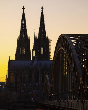 Cologne, Germany - February 17th 2020: A silhouetted view of Cologne Cathedral and the Hohenzollern Bridge in the historic city of Cologne, in Germany at Sunset.