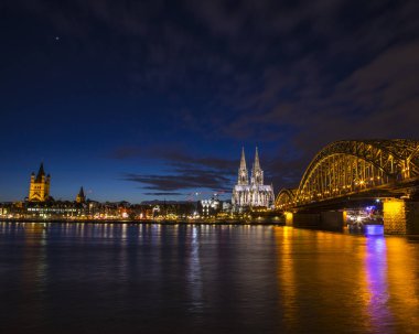 Venüs gezegeni, Almanya 'nın güzel Köln şehrinin üzerinde gece gökyüzünde. Köln Katedrali, Ren Nehri üzerinde uzanan Hohenzollern Köprüsü ve Büyük St. Martin Kilisesi görülebilir..