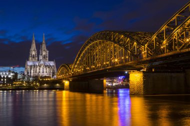 Köln Katedrali ve Almanya 'nın Köln kentindeki Ren Nehri üzerinde uzanan Hohenzollern Köprüsü' nün gece görüşü.
