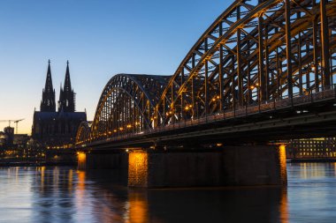 Köln Katedrali ve Almanya 'nın Köln kentindeki Ren Nehri üzerinde uzanan Hohenzollern Köprüsü' nün gece görüşü.