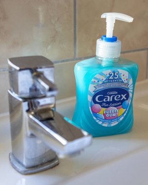 London, UK - March 12th 2020: Close-up of Carex Liquid Soap Hand Wash next to a tap in a bathroom.