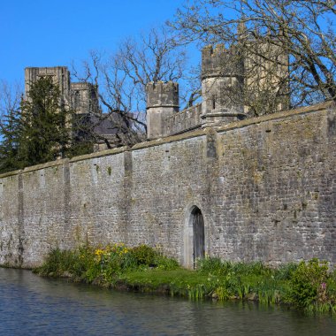 İngiltere 'nin Somerset kentindeki Wells kentindeki Bishops Sarayı' nın hendek ve çevre duvarının güzel bir manzarası var..
