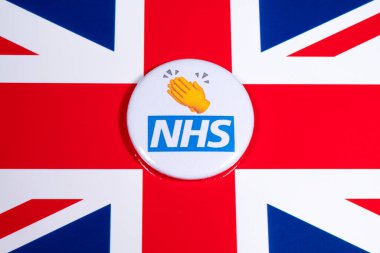 Londra, İngiltere - 5 Mayıs 2020: Ulusal Sağlık Servisinin logosunu gösteren bir rozet ve İngiltere bayrağı üzerinde bir alkış veya alkış sembolü.