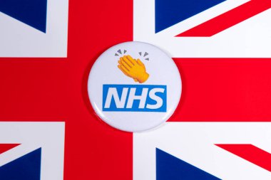Londra, İngiltere - 5 Mayıs 2020: Ulusal Sağlık Servisinin logosunu gösteren bir rozet ve İngiltere bayrağı üzerinde bir alkış veya alkış sembolü.