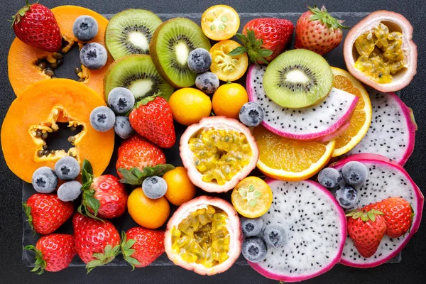 Fresh fruits. Exotic fresh fruits on a blackboard. Strawberry, blueberry, papaya, dragon fruit, kiwi, passion fruit.