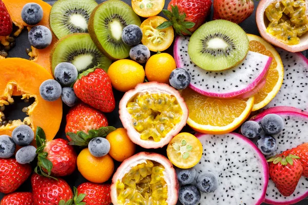 Fresh fruits. Exotic fresh fruits on a blackboard. Strawberry, blueberry, papaya, dragon fruit, kiwi, passion fruit.