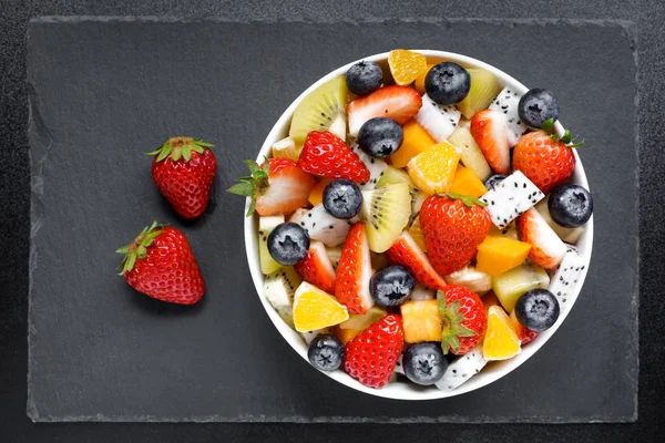 ダークウッドのテーブルに新鮮な果物からヘルシーなサラダ ボウル 新鮮なフルーツ イチゴ オレンジ ブルーベリー キウイ フルーツ パッション フルーツ — ストック写真