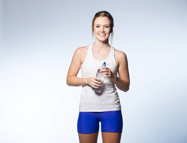 Vrouwelijke fitness model met waterfles op witte achtergrond. — Stockfoto