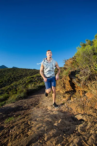 Modelo de fitness masculino correndo ao longo de uma trilha — Fotografia de Stock