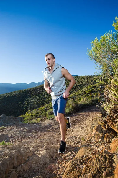 Male fitness model running along a trail