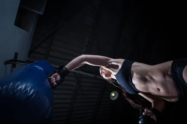 Boxeur femelle poinçonnant un sac de boxe — Photo