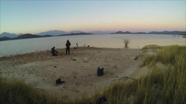 Fotógrafos em uma praia ao pôr do sol — Vídeo de Stock