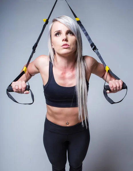 Sexy entrenamiento de modelo de fitness femenino en un dispositivo de entrenamiento en casa en — Foto de Stock