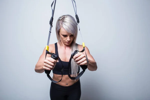 Sexy entrenamiento de modelo de fitness femenino en un dispositivo de entrenamiento en casa en — Foto de Stock