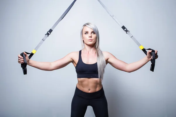 Sexy treinamento modelo de aptidão feminina em um dispositivo de treinamento em casa em — Fotografia de Stock