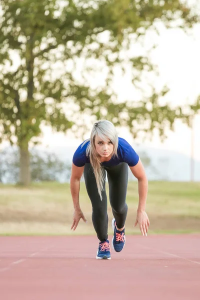 Atleta femenina corriendo en una pista de atletismo tartán — Foto de Stock