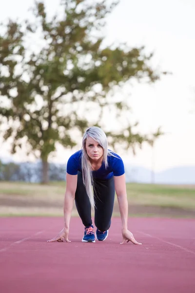 Atleta femenina corriendo en una pista de atletismo tartán — Foto de Stock