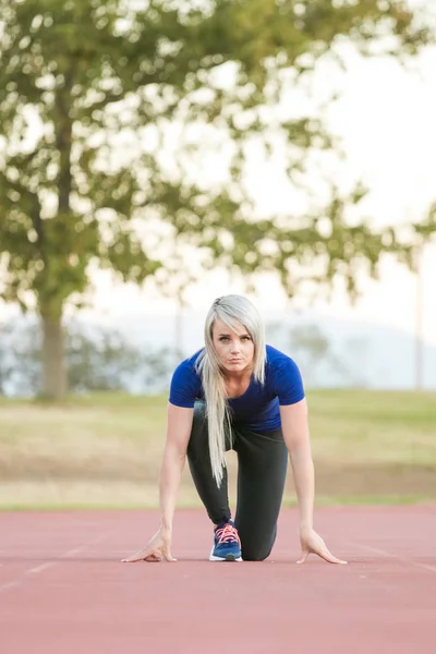 Atleta feminina sprint em uma pista de atletismo tartan — Fotografia de Stock