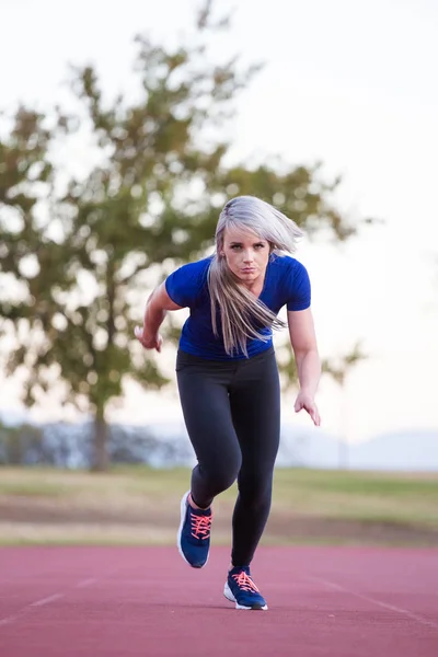 Atleta femenina corriendo en una pista de atletismo tartán — Foto de Stock