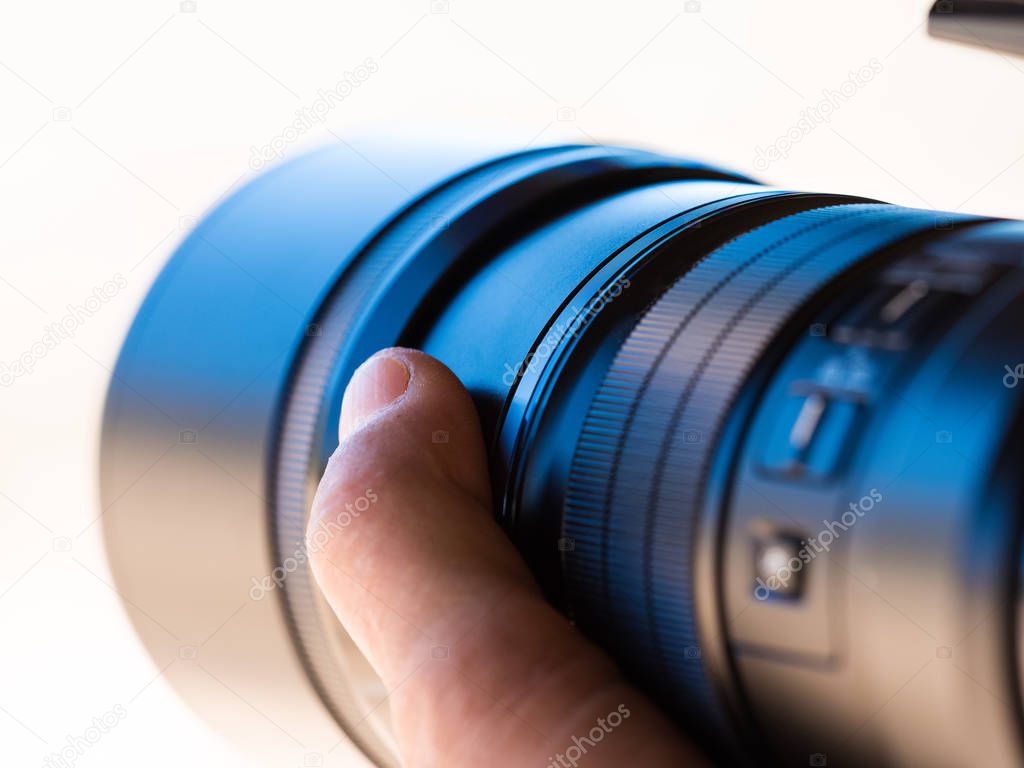 Close up of a camera telephoto lens being hand held by a photogr