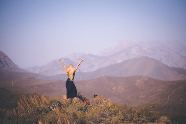Güzel sarışın kadın modeli duran manzarayı dağlarda arkadan görünüş