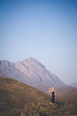 Güzel sarışın kadın model ayakta manzarayı dağlarda