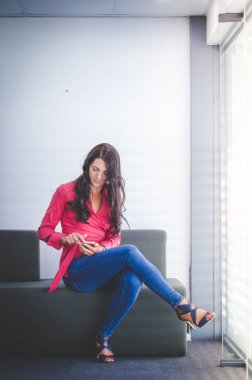 Çalışma ve mobil akıllı telefonunu kullanarak onun ofisinde oturan iş kadın